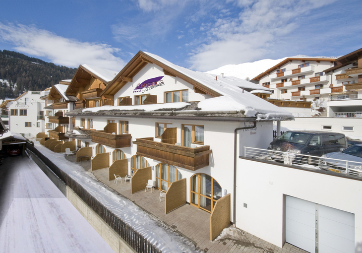 Hotel Amadeus Micheluzzi in Serfaus im Winter, Außenansicht mit verschneitem Dach.