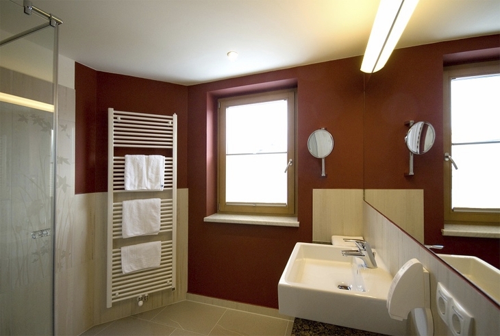 Modernes Badezimmer mit Doppelwaschbecken und roter Wand in Hotel Amadeus Micheluzzi.