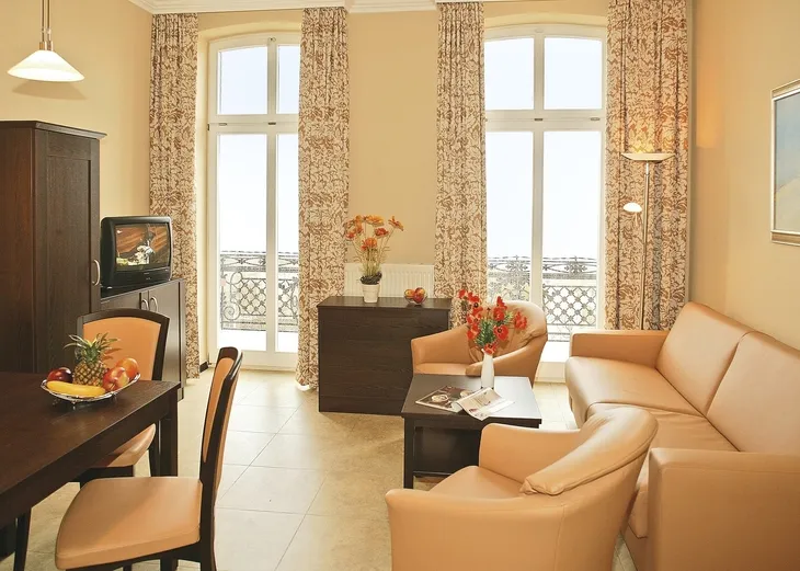 Helles Wohnzimmer mit Ledersofa, Esstisch und Blick durch große Fenster.