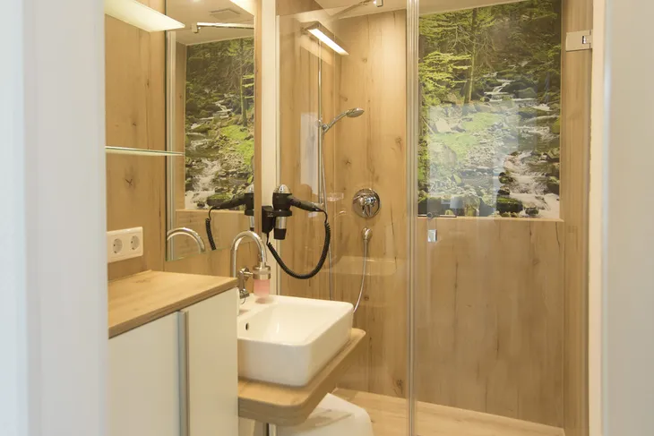 Modernes Badezimmer mit Holzdekor und Glasdusche.