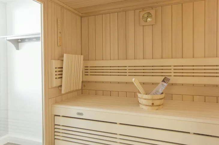 Innenansicht einer Holzsauna mit Saunaeimer und Thermometer.