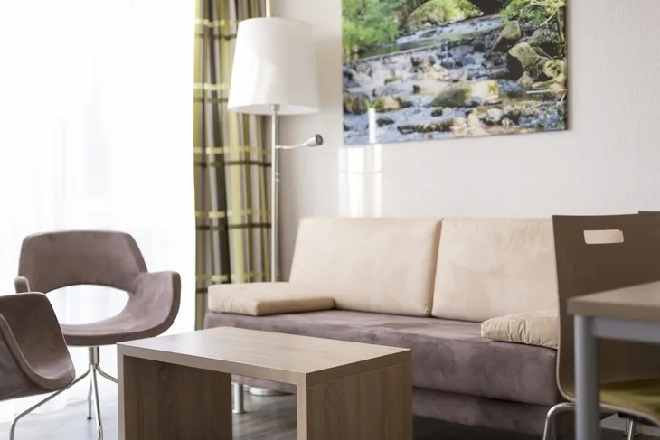 Modernes Wohnzimmer mit Sofa, Tisch, Stuhl und Landschaftsbild an der Wand.