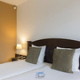 Hotelzimmer mit zwei Einzelbetten, Nachttisch und Lampe im Amrâth Hotel Alkmaar.