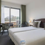 Hotelzimmer mit zwei Einzelbetten, Schreibtisch, Stuhl und TV.