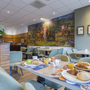 Hotelrestaurant mit gedecktem Frühstückstisch und Wandbild im Hintergrund.