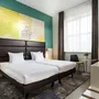 Modernes Hotelzimmer mit zwei Einzelbetten und bunten Wänden.