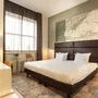 Hotelzimmer mit Doppelbett, Lampe, großem Fenster und Wandkunst in modernem Stil.