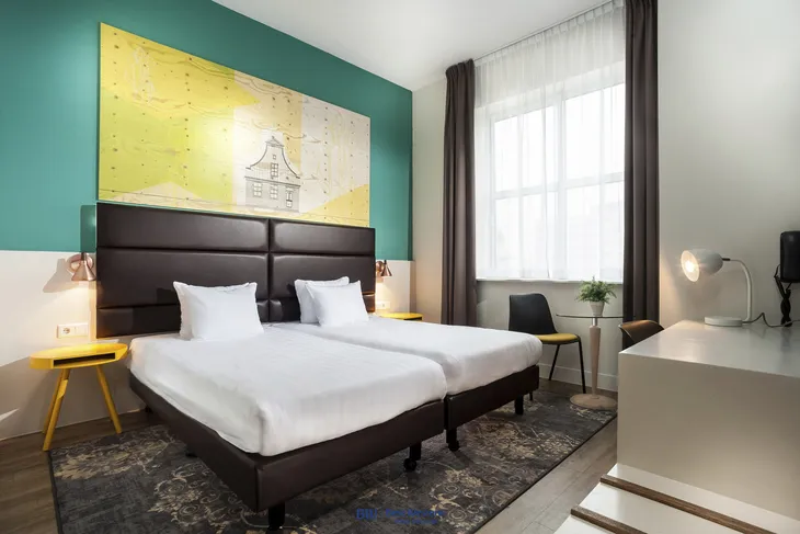 Modernes Hotelzimmer mit zwei Einzelbetten und bunten Wänden.