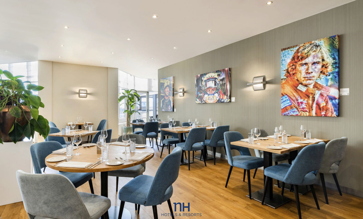 Innenansicht eines modernen Hotelrestaurants mit Tischen und Kunstwerken an den Wänden.