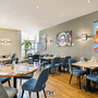 Innenansicht eines modernen Hotelrestaurants mit Tischen und Kunstwerken an den Wänden.