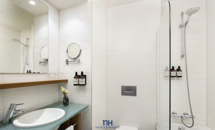 Modernes Badezimmer mit Dusche, Waschbecken, Spiegel und weißen Fliesen.
