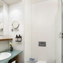 Modernes Badezimmer mit Dusche, Waschbecken, Spiegel und weißen Fliesen.