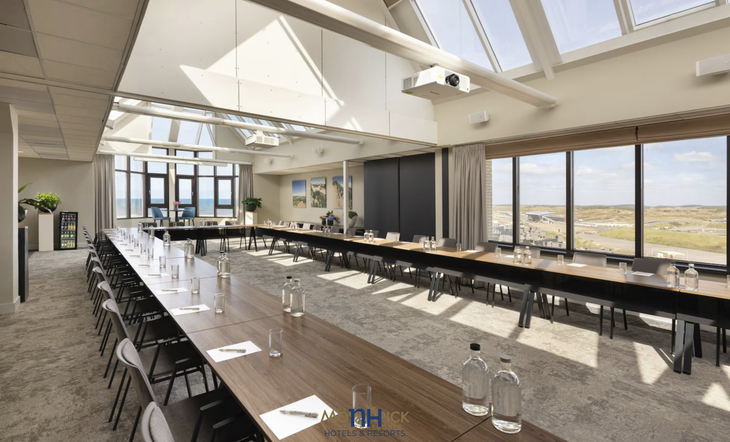 Konferenzraum mit U-förmigem Tisch und Panoramafenstern in einem Hotel.