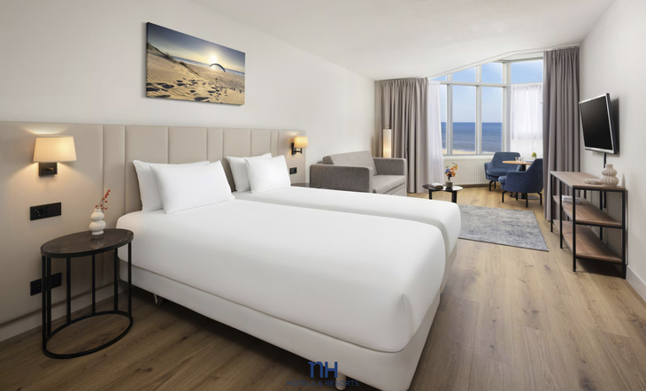 Modernes Hotelzimmer mit Meerblick, zwei Betten und Sitzbereich in Zandvoort.