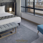 Innenansicht eines modernen Hotelzimmers mit Doppelbett und blauer Sitzgelegenheit.
