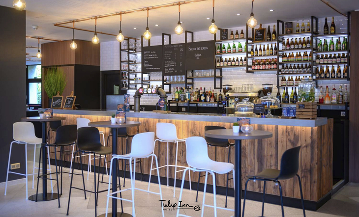 Moderne Hotelbar mit Barhockern und beleuchteter Theke.