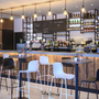 Moderne Hotelbar mit Barhockern und beleuchteter Theke.