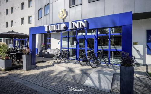 Eingangsbereich des Tulip Inn Hotels in Antwerpen mit blauen Elementen und Fahrrädern.
