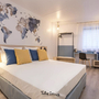Hotelzimmer mit Doppelbett, Weltkarten-Wanddeko und Schreibtisch in Antwerpen.