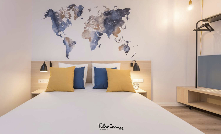 Modernes Hotelzimmer mit Doppelbett und Weltkarte an der Wand.