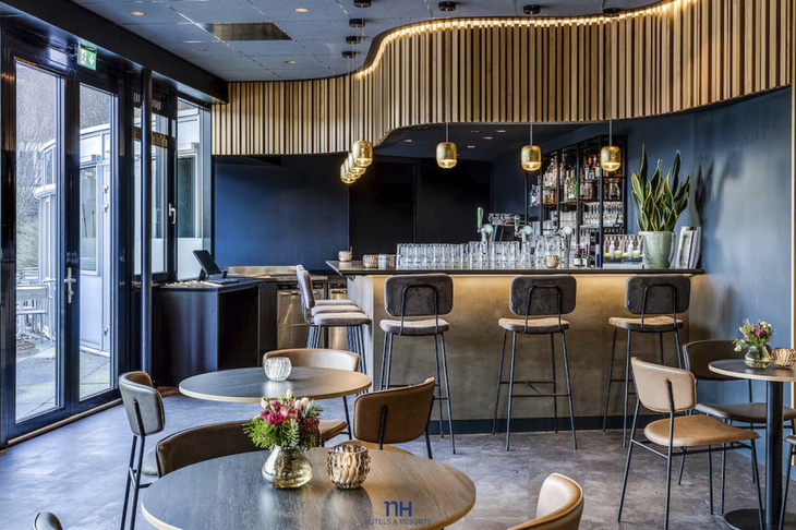 Moderne Bar mit schicken Hockern und Hängelampen, Blumen auf Tischen.