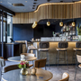 Moderne Bar mit schicken Hockern und Hängelampen, Blumen auf Tischen.