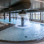 Poolbereich in einem modernen Innenraum mit Wasserfall und großen Fenstern.