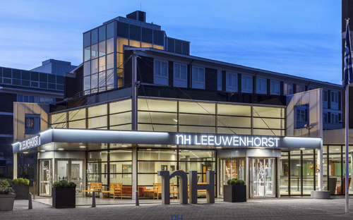 Eingangsbereich des NH Leeuwenhorst Konferenzzentrums in Noordwijk bei Abenddämmerung.