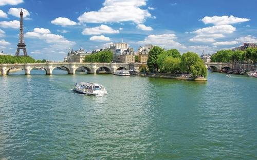 Blick auf die Seine mit Eiffelturm und Brücke in Paris bei sonnigem Wetter.