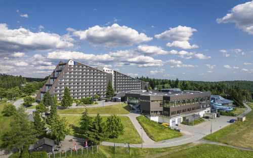 Außenansicht des IFA Schöneck Hotel und Ferienparks bei sonnigem Wetter.