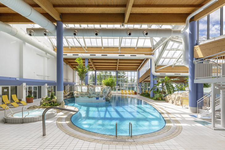 Innenansicht eines Hallenbads mit Pool und Liegen im IFA Schöneck Hotel.