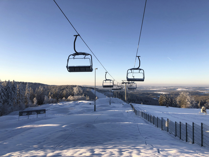Sessellift über verschneiter Landschaft im Skiwelt Schöneck, blauer Himmel im Hintergrund