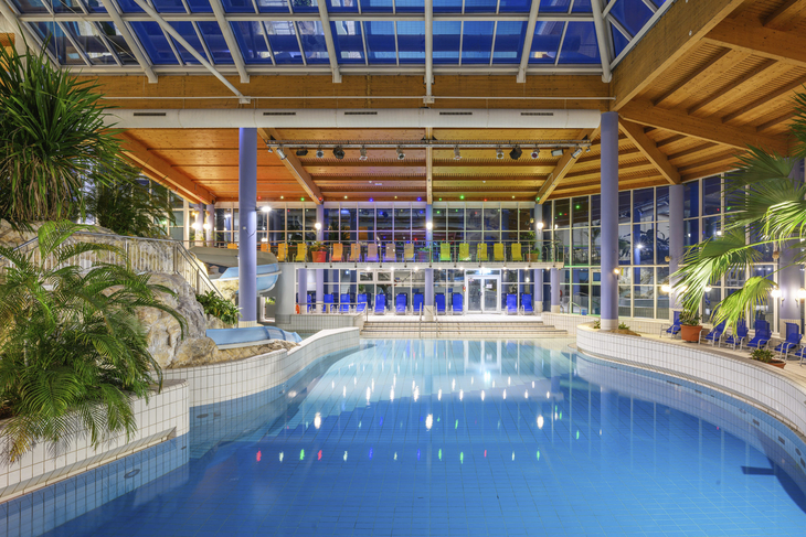 Innenansicht eines Hotelpools mit Glasdach und Pflanzen im Schöneck Hotel und Ferienpark.