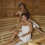 Zwei Personen in einer Sauna, mit Handtüchern bekleidet.