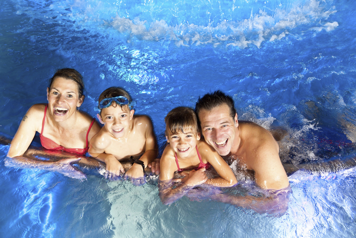 Familie schwimmt lächelnd im Pool des JUFA Hotels in Kempten.