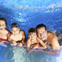 Familie schwimmt lächelnd im Pool des JUFA Hotels in Kempten.