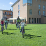Menschen fahren Fahrrad vor JUFA Kempten Familien-Resort auf grüner Wiese.