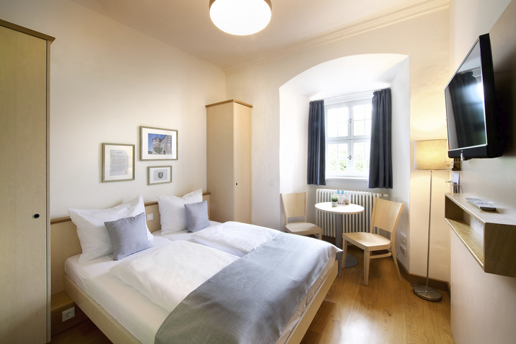 Helles Einzelzimmer im JUFA Hotel Kronach mit Bett, Fenster und Möbeln.
