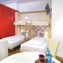 Zwei Einzelbetten und ein Hochbett in einem Hotelzimmer mit hellem Holzinterieur.