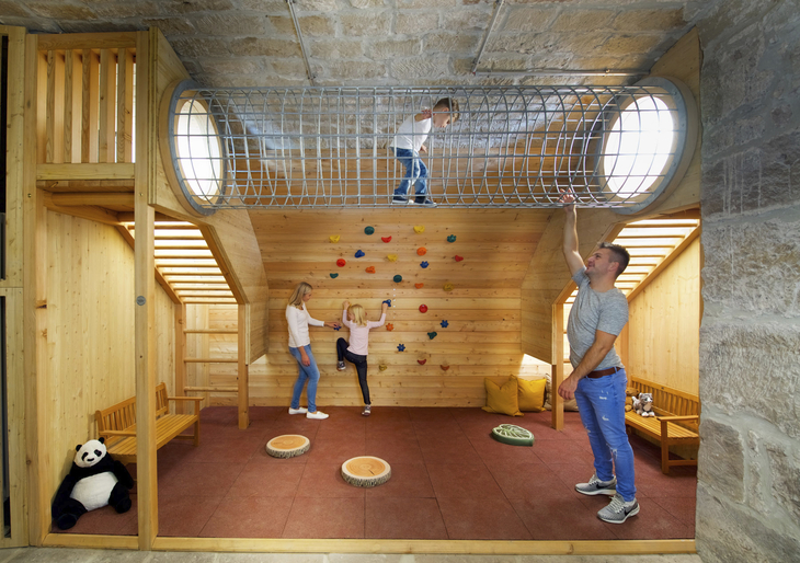 Spielzimmer mit Kletterröhre und Kletterwand, Kind beim Klettern im JUFA Hotel Kronach.