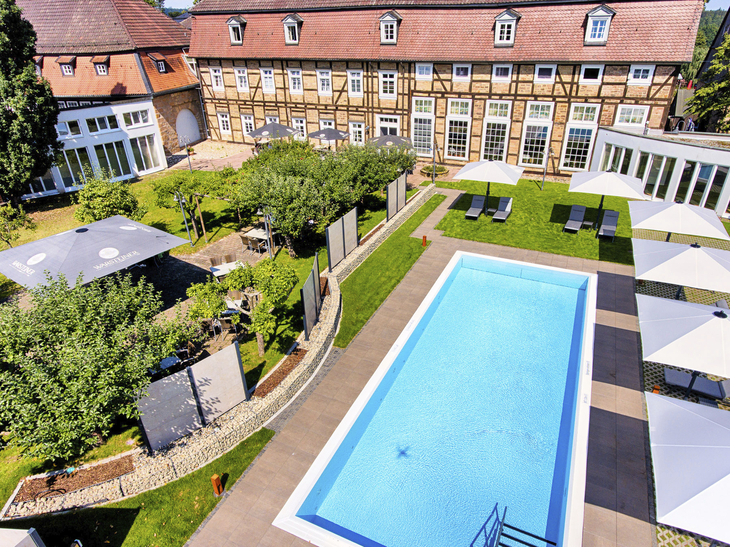 Außenansicht mit Pool und historischem Gebäude im Welcome Hotel Bad Arolsen.