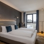 Hotelzimmer mit Doppelbett, Fenster, Fernseher und moderner Einrichtung.
