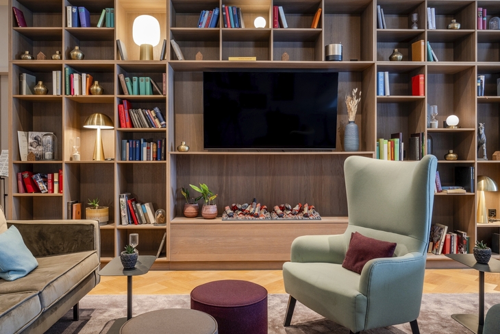 Wohnzimmer mit Regalwand, Sessel, Sofa und Dekorationen.
