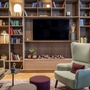 Wohnzimmer mit Regalwand, Sessel, Sofa und Dekorationen.