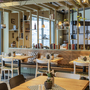 Modern eingerichtetes Hotelrestaurant mit Holztischen und Stühlen.