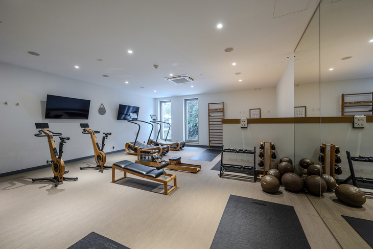 Fitnessraum mit Fahrradergometern, Laufband, Gewichten und Spiegelwand im Hotel.
