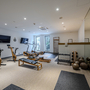 Fitnessraum mit Fahrradergometern, Laufband, Gewichten und Spiegelwand im Hotel.