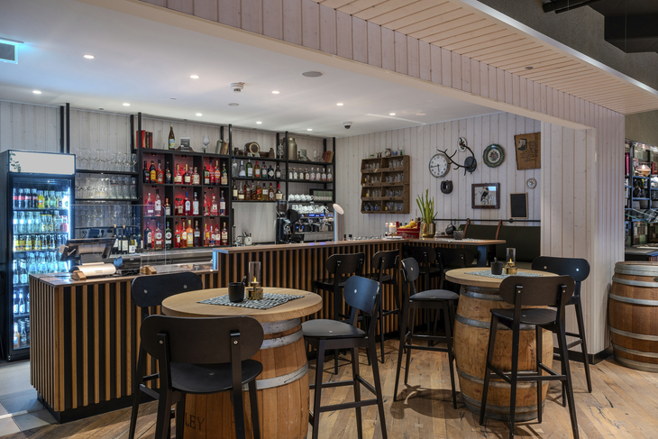 Hotelbar mit Holzmöbeln, Tischen und einer Wand voller Getränke.