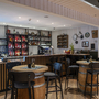 Hotelbar mit Holzmöbeln, Tischen und einer Wand voller Getränke.