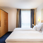 Hotelzimmer mit zwei Einzelbetten, modernem Dekor und großem Fenster.